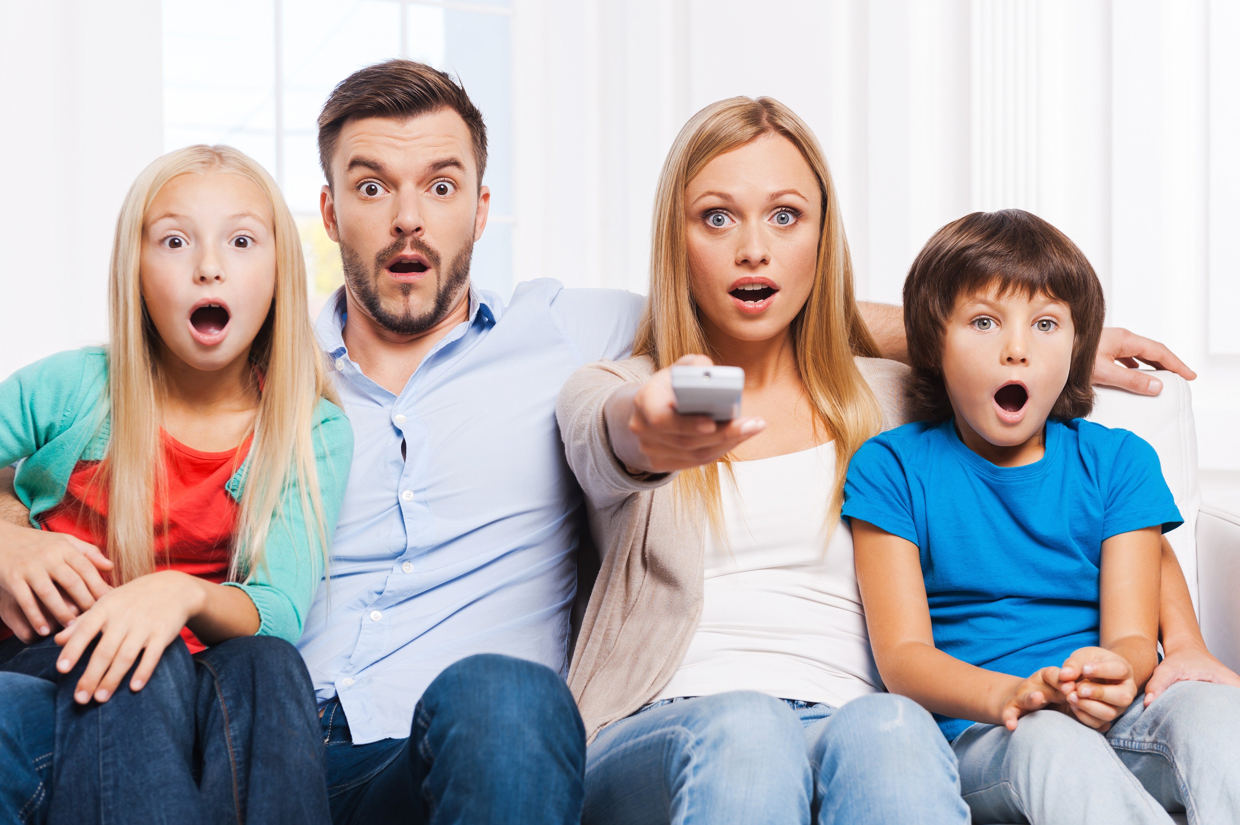 Представляет огромный интерес. Семья у телевизора. Семья перед Телеком. Веселая семья. Удивленные дети.
